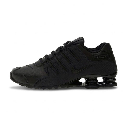 Lateral profile view of the Nike Shox NZ Black sneaker featuring a black synthetic leather and mesh upper, tonal Nike Swoosh, integrated ghillie lacing, and black Shox cushioning columns in the heel.