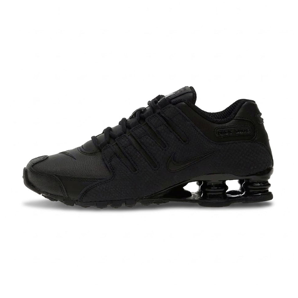Lateral profile view of the Nike Shox NZ Black sneaker featuring a black synthetic leather and mesh upper, tonal Nike Swoosh, integrated ghillie lacing, and black Shox cushioning columns in the heel.